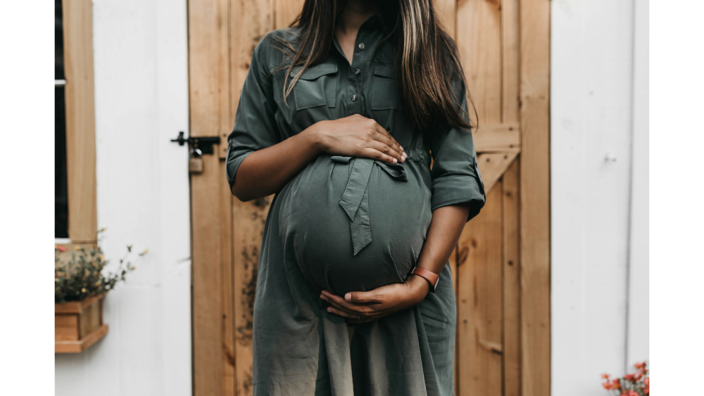 A pregnant woman standing in front of her home